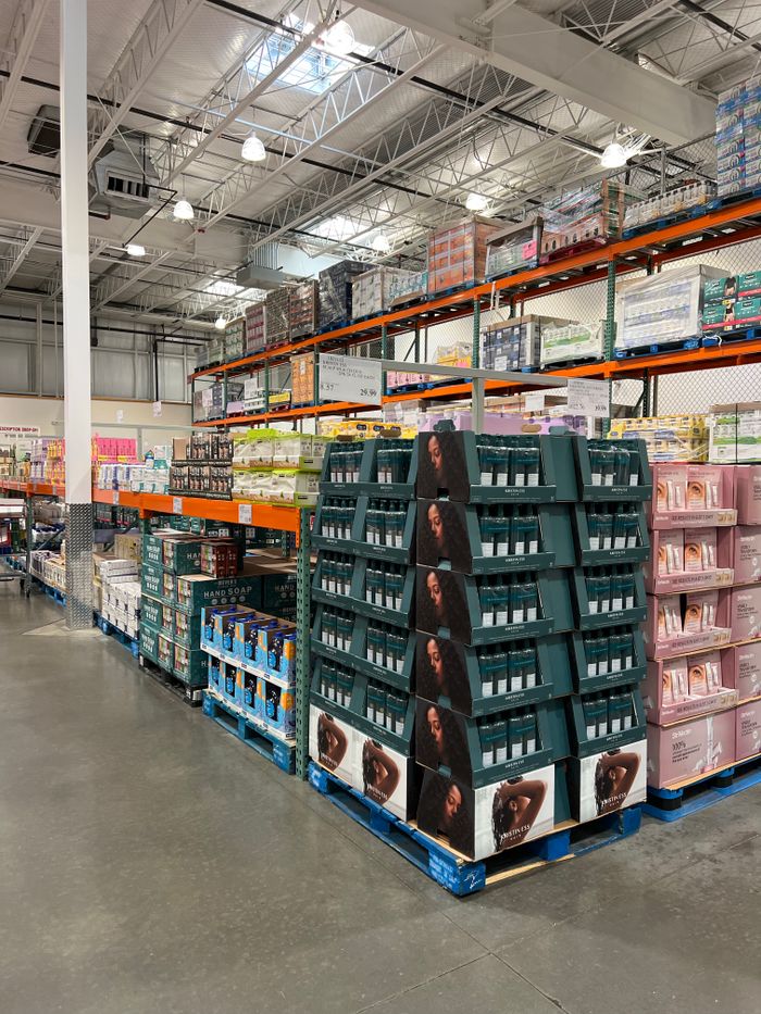 Home A spacious warehouse aisle with shelves full of health products, industrial lighting.