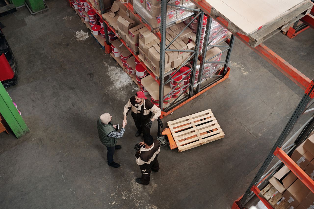 Home High angle view of workers discussing logistics in a warehouse setting.