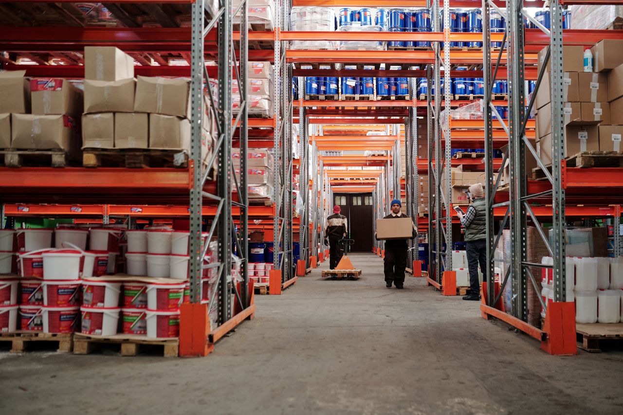 Home Warehouse interior showing workers handling boxes and organized shelves filled with products.